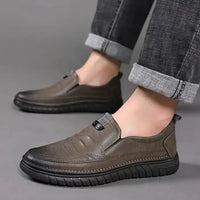 Brown leather shoes worn with rolled-up jeans on a gray background