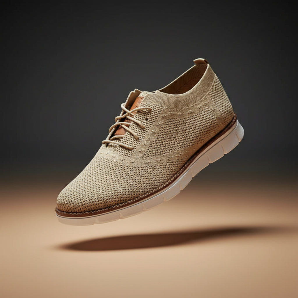 Beige sneaker with white sole held by a hand against a blurred background