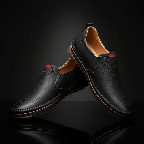 Black leather shoes with brown soles on a light gray background