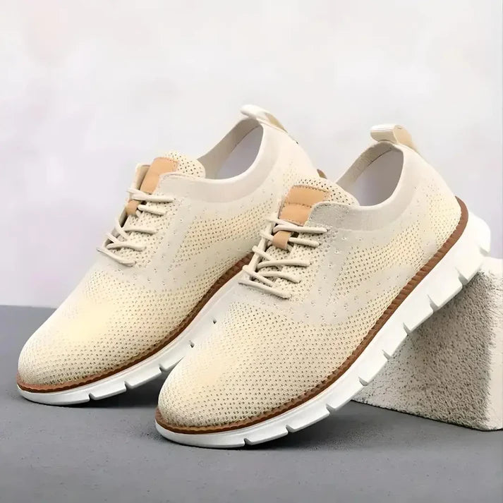 Pair of cream-colored sneakers with brown accents on a gray surface.