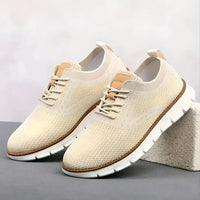 Pair of cream-colored sneakers with brown accents on a gray surface.