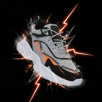 Gray and black sneaker with orange accent on a white background
