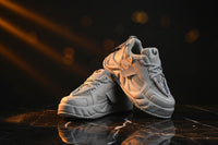 White sneakers with gray laces on an orange background