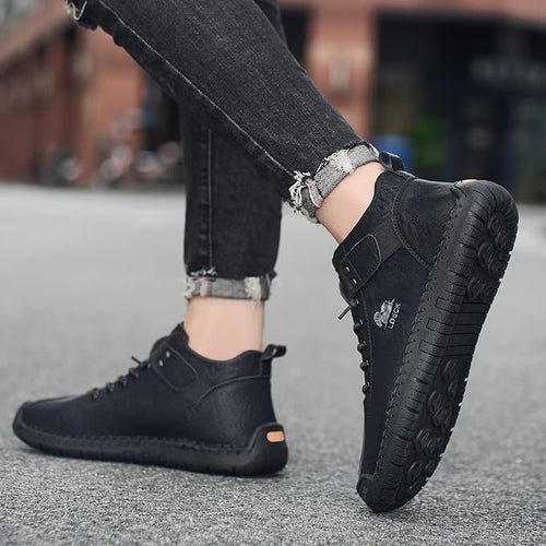 Black leather shoes worn with black jeans on a blurred street background