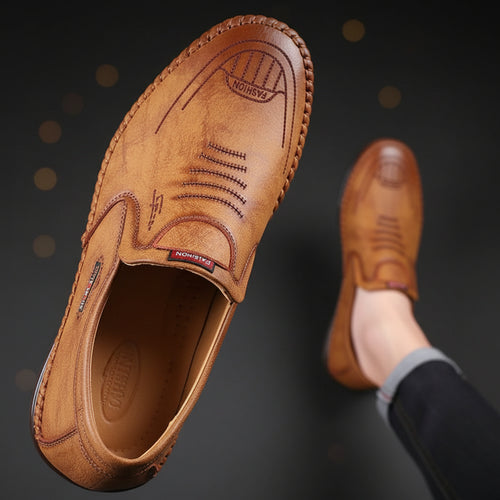Brown leather shoes worn by a person on a gray background